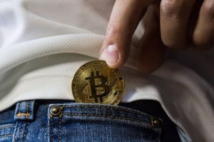 bitcoin wsuwany kieszeń jeansy dłoń trzyma monetę